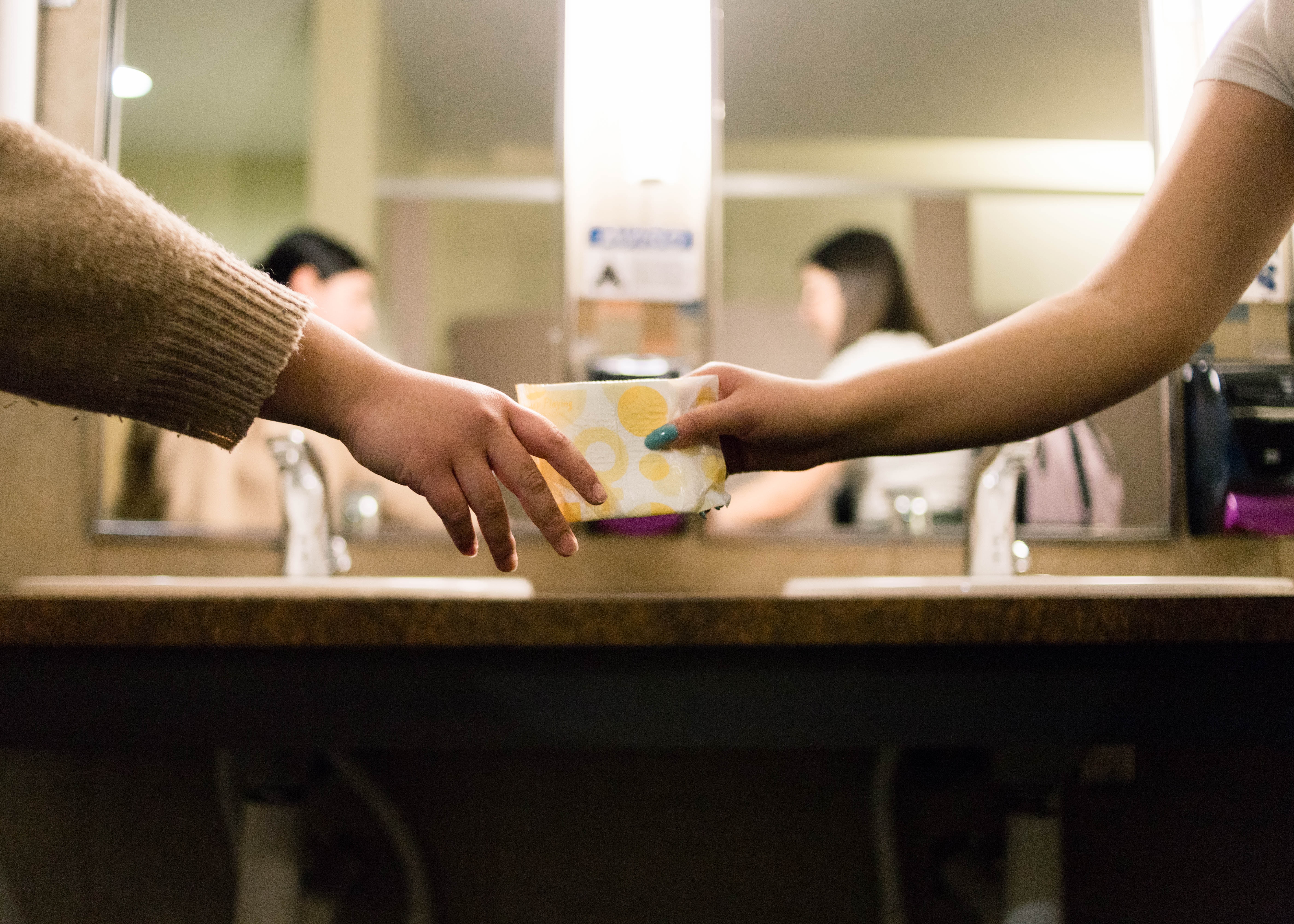 Une femme donnant une serviette hygiénique gratuite à une autre femme